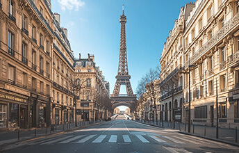 View of the Eiffel Tower from an empty street lined with classic Parisian buildings on a clear day in Paris, France.