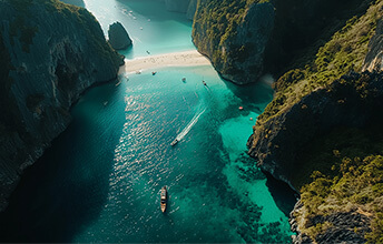 Aerial view of Maya Bay in the Phi Phi Islands, Thailand, showcasing turquoise waters, sandy beach, and limestone cliffs, with boats navigating the bay.